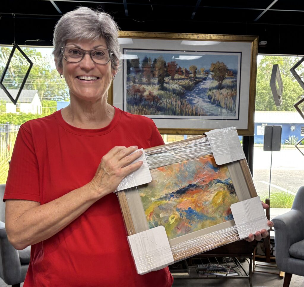 Kim McCauley holding her original abstract acrylic painting And Then the Mountain Spoke